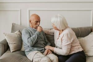Managing risks in assisted living investments: Senior man and woman sitting on a couch in a community room. 