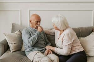 Managing risks in assisted living investments: Senior man and woman sitting on a couch in a community room.